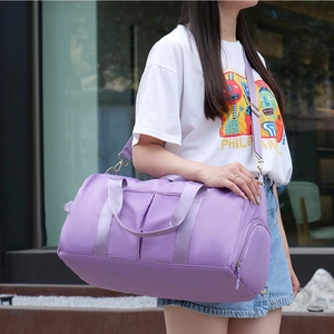 Large purple travel fitness bag with dry-wet separation carried by model outdoors