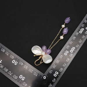 Elegant butterfly drop earrings with natural pearls and purple tassels on black texture