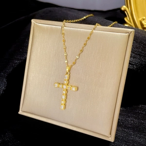 Titanium steel gold cross necklace with clear zircons on a luxury cushion display