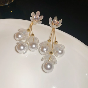 Vue macro de boucles d'oreilles fleur dorées avec cristaux et pendentif perle crème