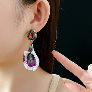 Macro shot of vintage enamel calla lily earrings with crimson gemstones and green crystals