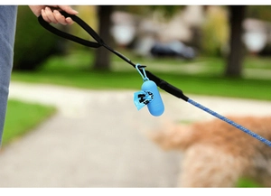 Blue capsule dog poop bag dispenser with LED light hanging on a leash in park