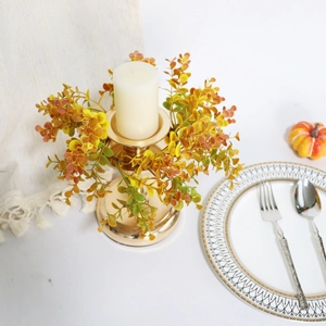 Close-up of golden candle holder with autumn maple leaves and berries centerpiece decor
