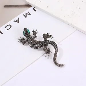 Macro detail of lizard brooch with grey rhinestones and green gem eyes on stone