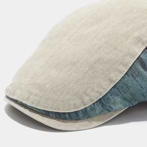 Detail of a distressed patchwork flat cap showing khaki twill and blue denim brim