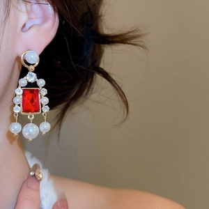Détail de boucles d'oreilles vintage avec perles et pierres rouges portées par un mannequin