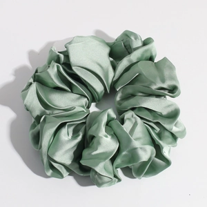 Detailed view of a single green satin silk scrunchie with smooth glossy texture and pleats