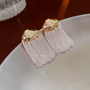 Détail de boucles d'oreilles en métal martelé doré avec de fines franges argentées