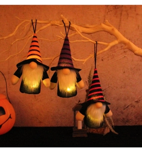 Three glowing Halloween gnome hanging ornaments with striped hats and warm festive lighting