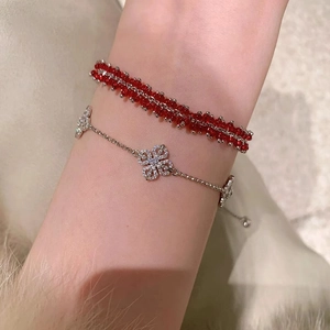 Detail of red beaded bracelet and silver clover charm bracelet with sparkling crystals