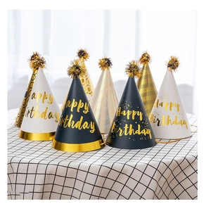 Black and white birthday party hats with gold foil Happy Birthday text and pom poms