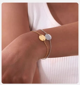 Detail showing gold and silver stainless steel chain bracelets with round pendant on wrist