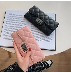 Detail of quilted leather long wallets in black and pink with metal twist lock closure