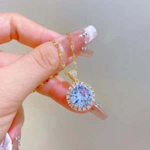 Close-up of golden necklace with a brilliant round zircon halo pendant held in hand