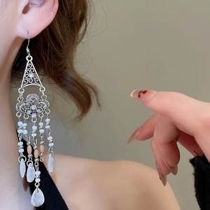 Ethnic style silver tassel earrings with white beads on model in soft lighting