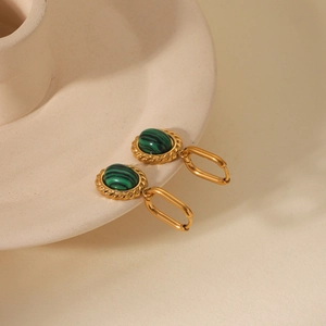 Close-up of vintage gold twist earrings featuring oval green malachite stones on ceramic