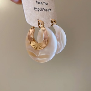 Macro detail of French vintage earrings with gold textured metal and marble resin pendants