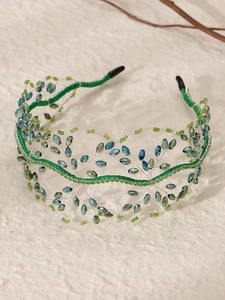 Dettaglio di cerchietto verde artigianale con perline di cristallo e maglia intrecciata