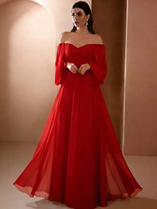 Dettaglio dell'abito da sera rosso con spalle scoperte, maniche a lanterna e gonna in chiffon