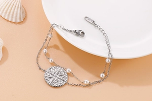 Detail view of double-layer stainless steel bracelet with white pearls and star pendant