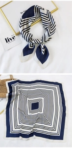 Detail of navy blue and white geometric striped silk scarf laid on a minimalist background