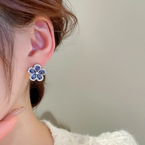 Close-up of vintage blue zircon flower earrings with silver plating on model