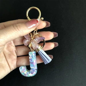 Resin letter J keychain with purple tassel, golden butterfly, and heart sequins detail