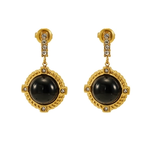 Détail de boucles d'oreilles vintage dorées avec pierre noire et cristaux brillants