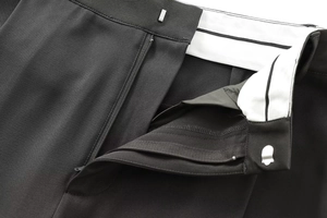 Détail macro du pantalon noir montrant la fermeture à glissière et le crochet métallique