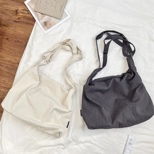 Detailed close-up of pleated canvas shoulder bags in creamy white and dark grey colors