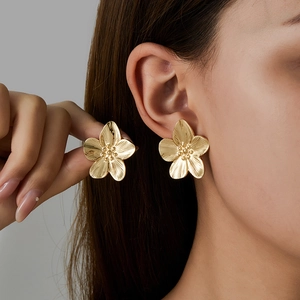 Detail of 18K gold plated flower stud earrings shown on model for a luxury textured look