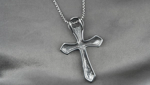 Macro shot of vintage silver cross pendant with intricate patterns on box chain