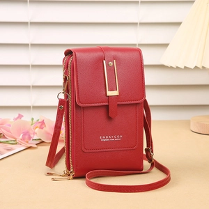 Detail of red faux leather phone bag with golden buckle and textured finish on a desk