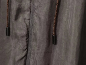 Macro detail of dark grey twill fabric with brown braided drawstrings and gunmetal tips