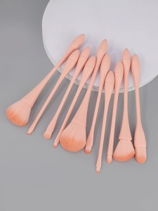Detailed set of 10 orange-pink makeup brushes with fluffy bristles on a display stand