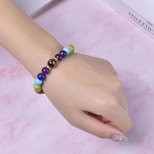 Chakra stone bracelet with matte beads and gold Mantra symbol on pink background