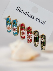 Three pairs of floral enamel hoop earrings in blue, red, and black on a display card
