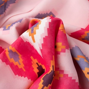 Detailed macro view of ethnic geometric pattern fabric in pink, white, and orange