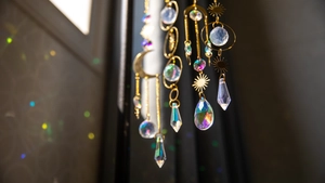 Close-up of brass suncatcher with crystal prisms reflecting rainbow light at window