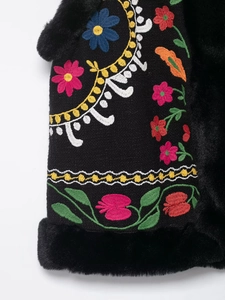 Nahaufnahme der floralen Stickerei und des schwarzen Kunstfellbesatzes an der Weste