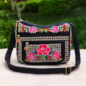 Close-up of vibrant floral embroidery and gold zippers on a black ethnic crossbody bag