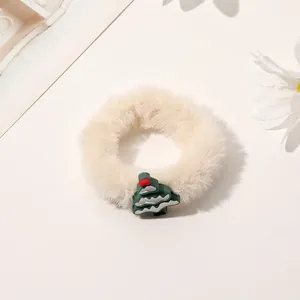 Detailed view of plush cream scrunchie with a festive green Christmas tree charm