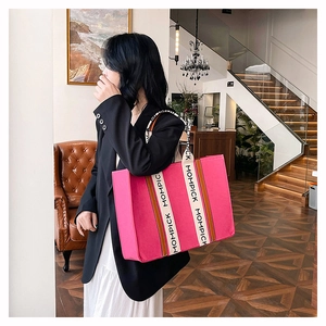 Detail of pink canvas tote bag with MOMPICK embroidery and wide woven handles on the side