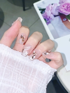 Macro detail of luxury press-on nails with butterfly patterns, pearls and crystals