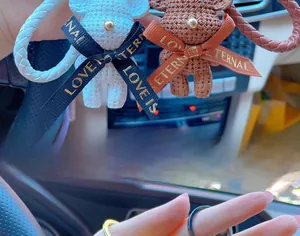 Detail of cute white and brown resin bears with woven lanyards for car interior decor