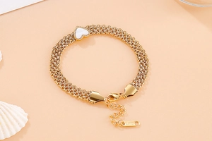 Detail of gold multi-layer chain bracelet featuring a white heart shell inlay