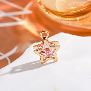 Macro detail of a 14K gold-filled star pendant with a pink zircon on a stone base