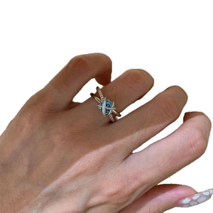 Elegant silver crisscross ring featuring a sea blue gemstone and sparkling zircons