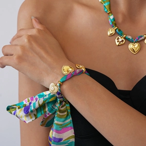 Detailed shot of printed silk scarf necklace and bracelet with golden heart charms