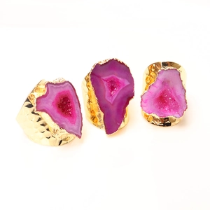 Macro view of three irregular pink druzy agate rings with gold plated textured bands